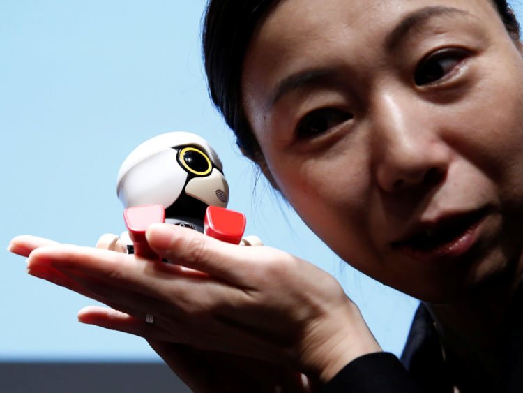 A staff member listens to Toyota Motor Corp's Kirobo Mini robot's voice as she poses with the robot after a news conference in Tokyo, Japan, September 27, 2016. Picture taken on September 27, 2016.REUTERS/Kim Kyung-Hoon - RTSQH3E